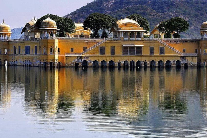 A palace with domed structures and arched walkways over a calm lake. 3
