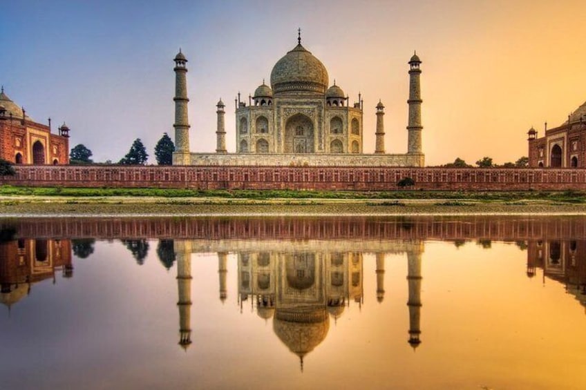The Taj Mahal with its reflection in the water, surrounded by a red wall and minarets. 1