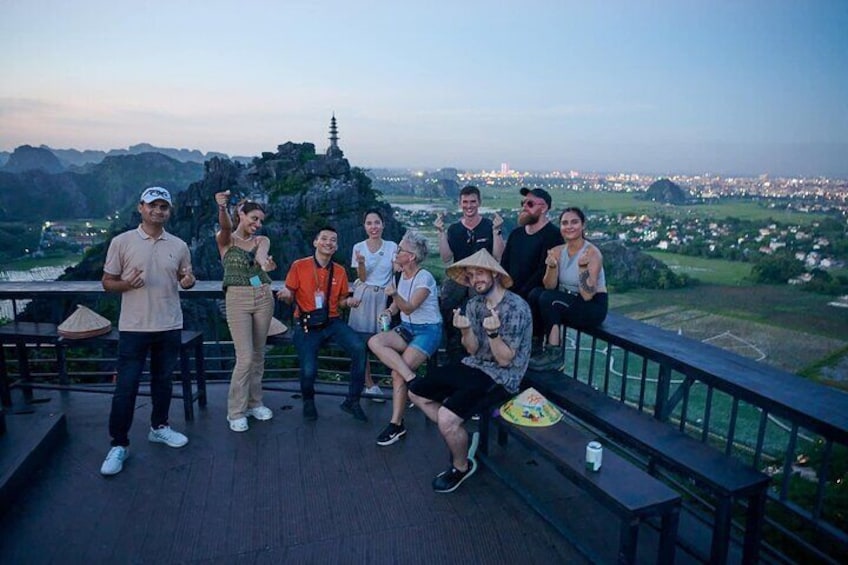 A group of people on a viewing platform overlooking a landscape with a prominent temple-like structure. 1
