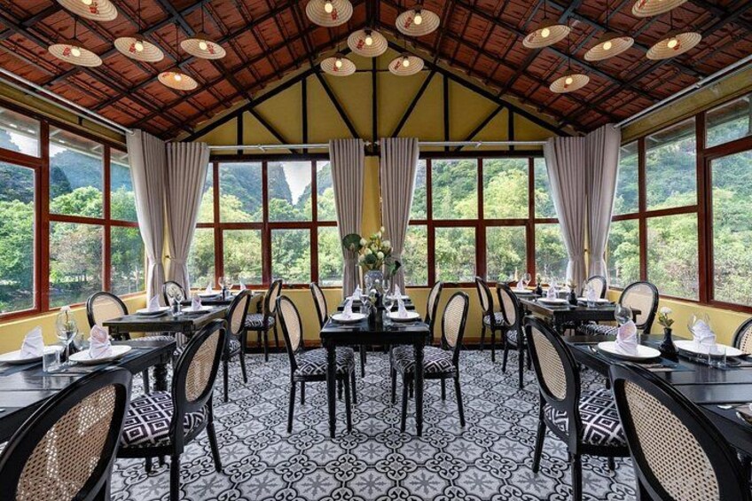 A dining area with tables and chairs, large windows, and a patterned floor. 1