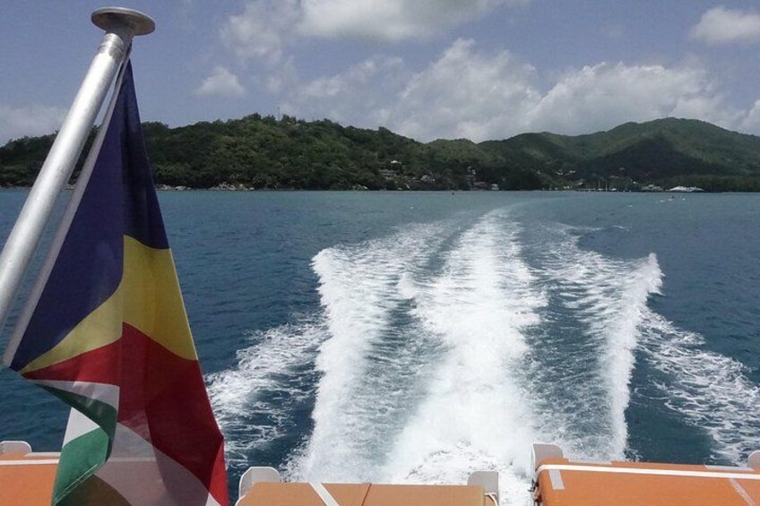 A boat moving through water with a wake, a flag, and a mountainous landscape in the background. 2