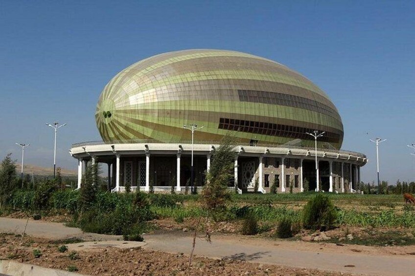A large, dome-shaped building with a reflective surface, surrounded by greenery and a clear sky. 5
