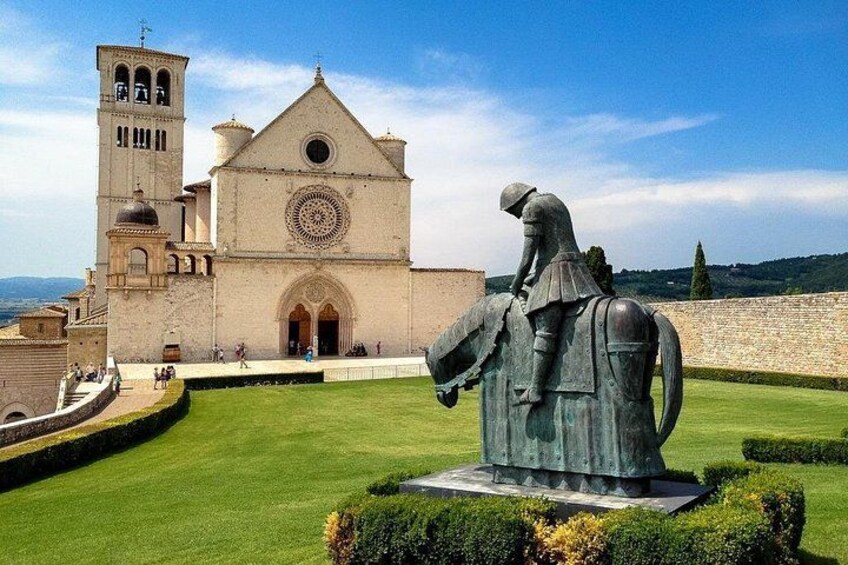 A statue of a knight on horseback, a church with a bell tower, and a well-manicured lawn. 1