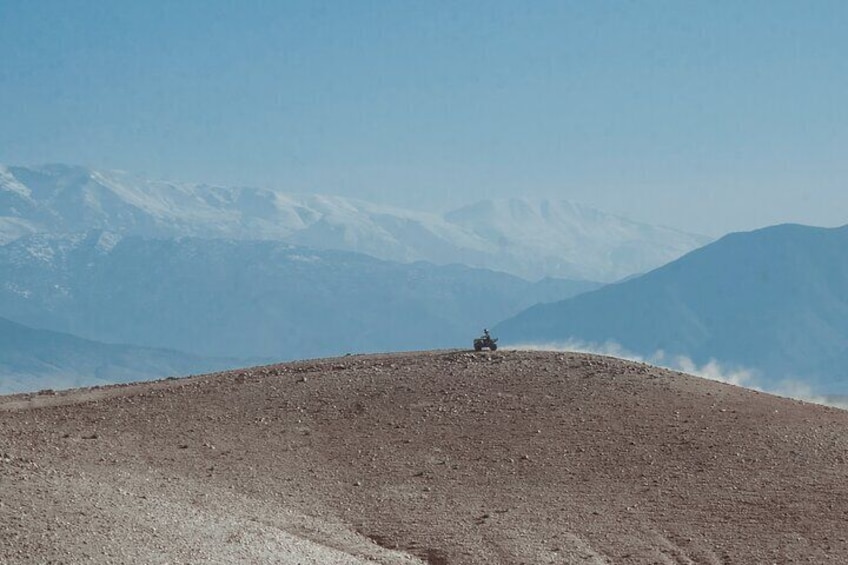 A vehicle on a mountain ridge with snow-capped peaks in the background. 4