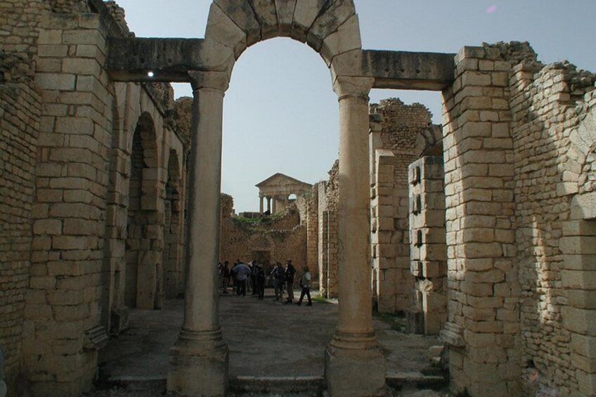 Un antiguo arco de piedra con columnas, que conduce a un edificio con cúpula. 4