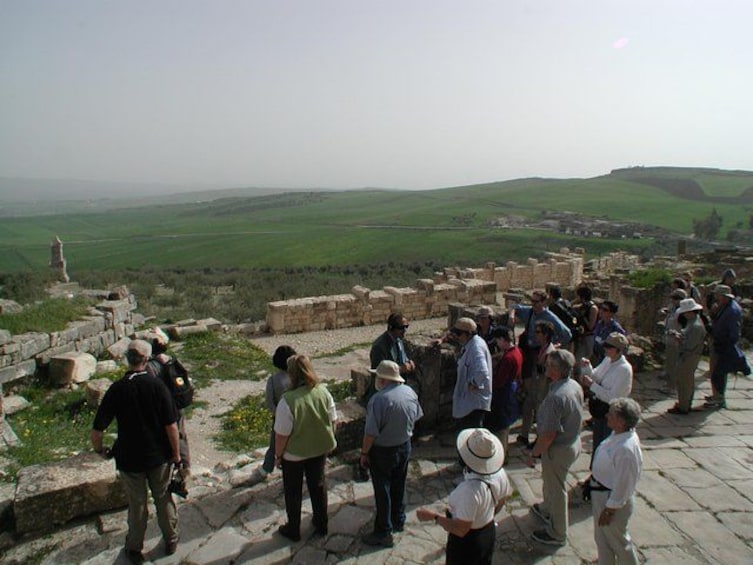 Un grupo de personas sobre ruinas antiguas contemplando un paisaje verde. 3