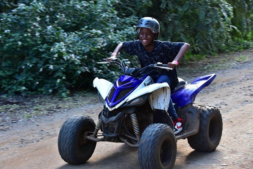 A person riding a quad bike on a dirt road surrounded by greenery. 2