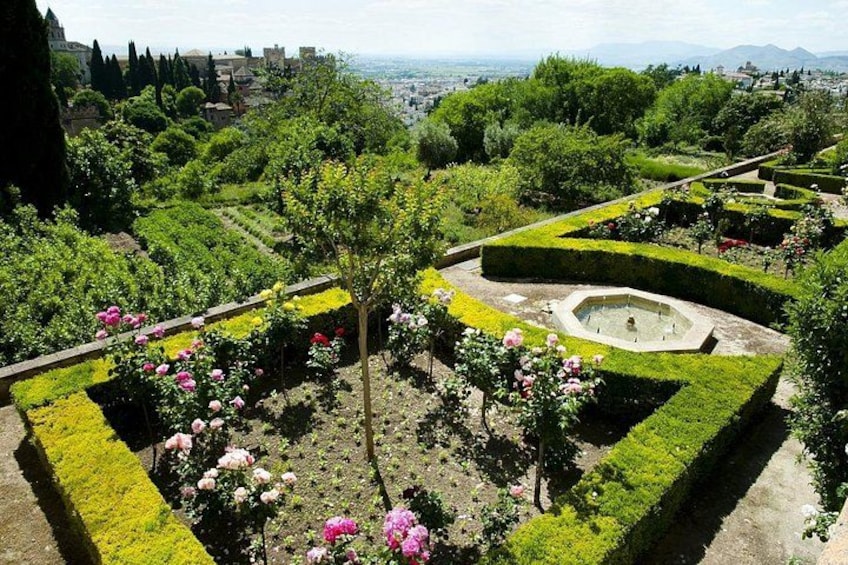Ein gepflegter Garten mit geometrischen Hecken, blühenden Pflanzen und einer zentralen Fontäne. 5
