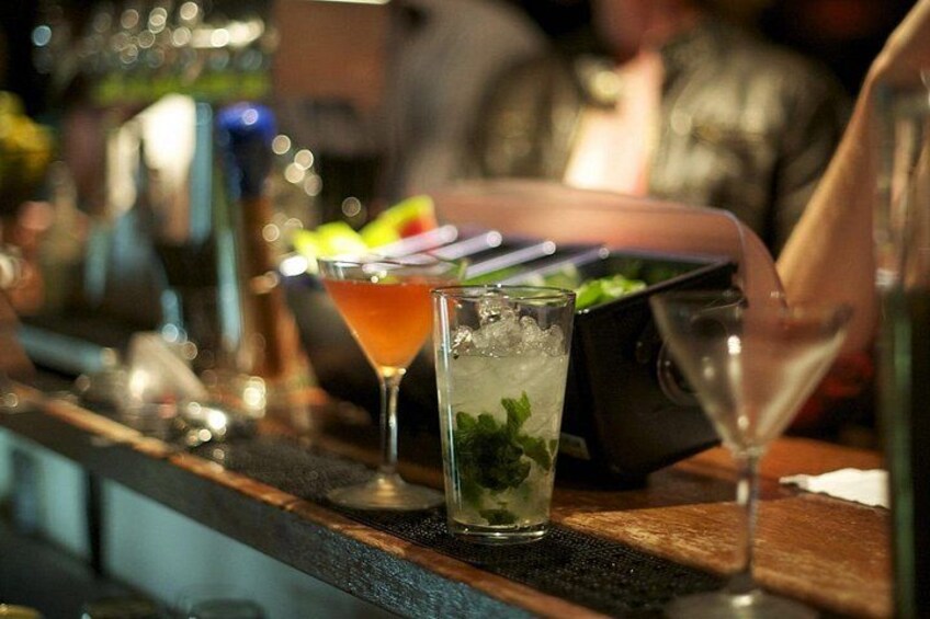 Un bar con diversas bebidas, incluyendo un martini y un cóctel con hielo y menta. 5