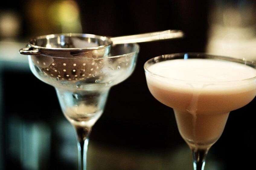 Dos vasos de martini, uno con pajita y otro sin, y un colador metálico. 4