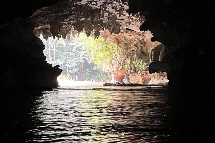 A cave entrance with water reflecting light, a rocky interior, and a view of trees outside. 5