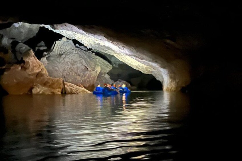 A cave with a water body and a group of people in a blue raft. 4