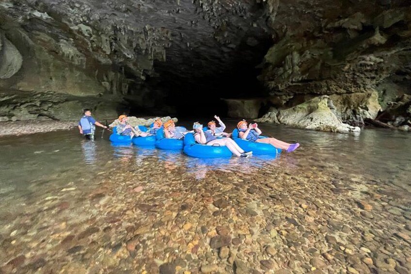 People floating in blue rafts in a clear river within a cave. 3