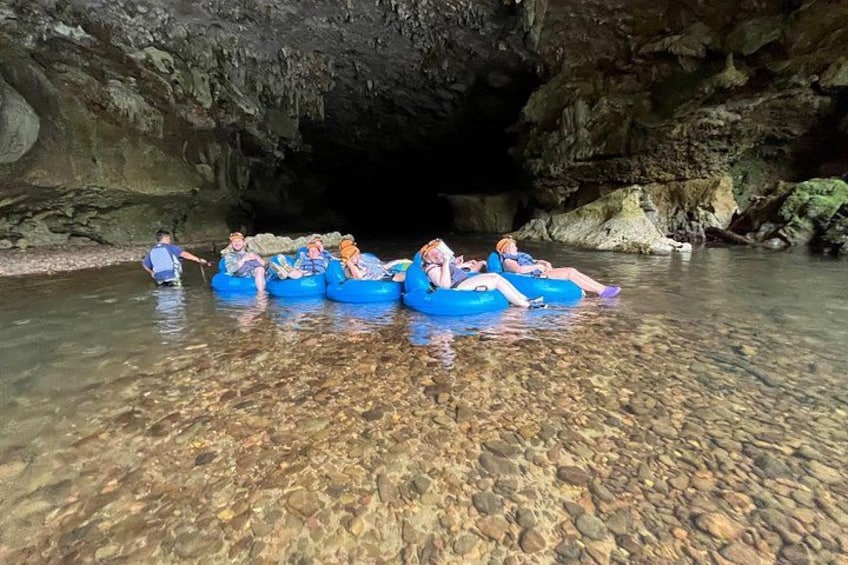 People floating in blue tubes in a clear water cave. 2