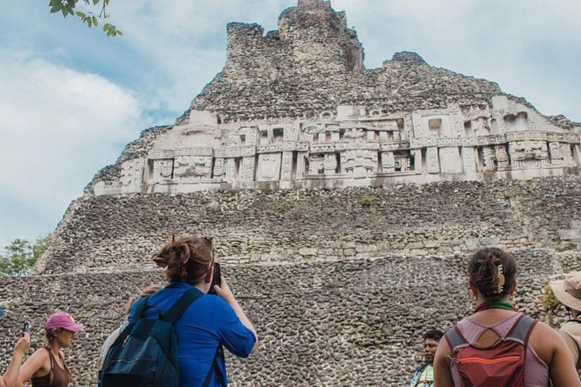 A large ancient stone structure with carvings, surrounded by tourists. 2