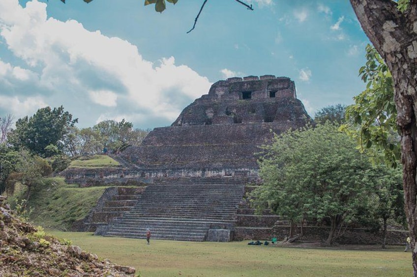 A large ancient pyramid with steps leading up to it, surrounded by trees and a clear sky. 4