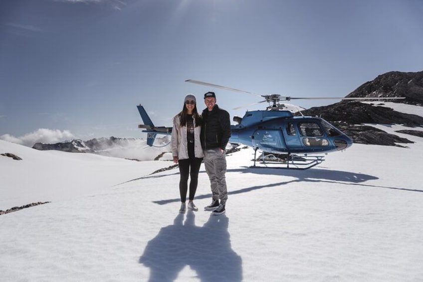 A person standing in front of a helicopter on a snowy mountain. 3