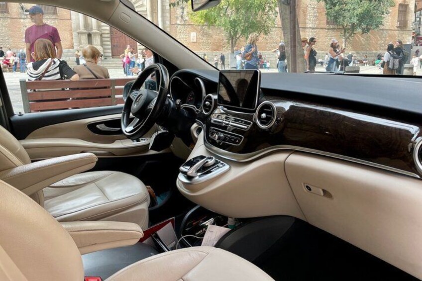 El interior de un coche con asientos de cuero color beige, un volante, una consola central con pantalla táctil y palanca de cambios. 5
