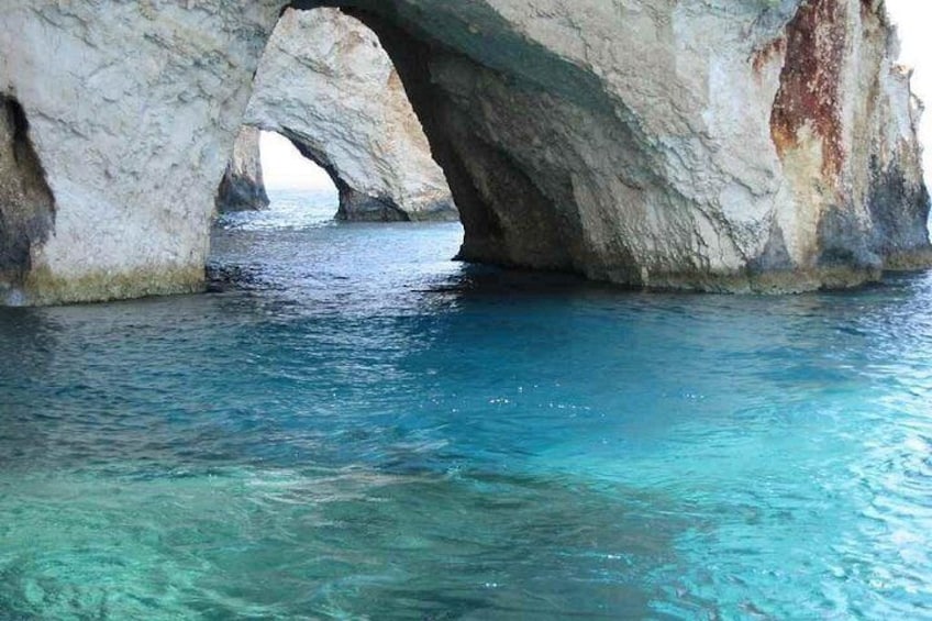 A natural rock formation with a clear blue water body underneath. 4