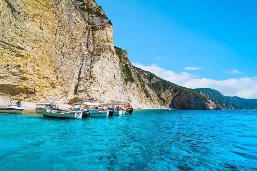 Boats docked at a rocky coastline with clear blue water. 5