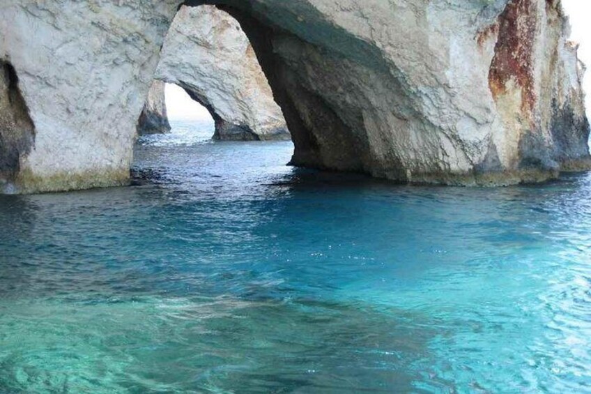 A natural rock formation with a clear blue water body beneath it. 4