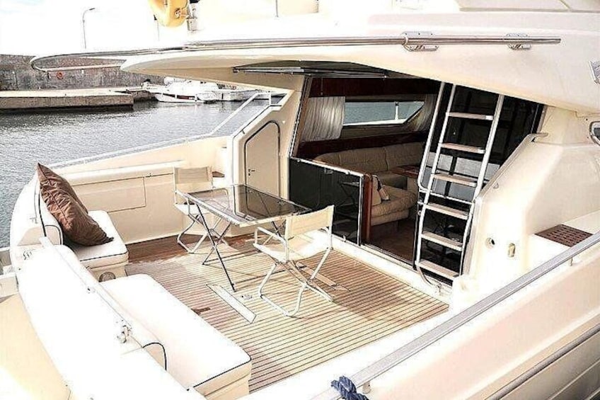 A yacht's deck with a table, chairs, and a ladder. 1