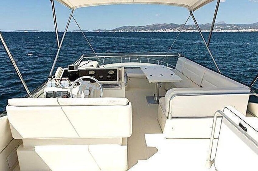 A boat's interior with a steering wheel, control panel, and seating area. 5