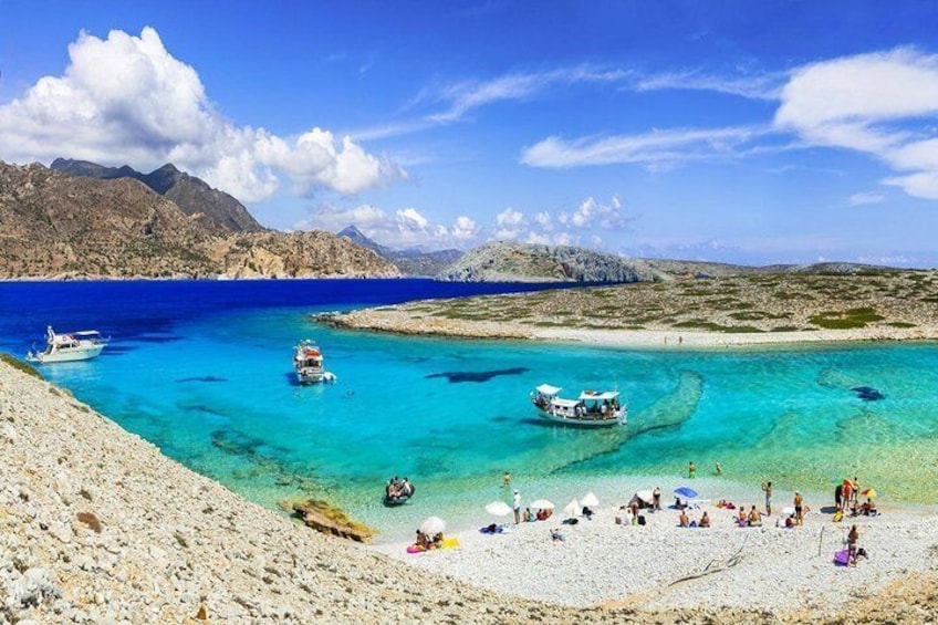 A beach with clear turquoise waters, boats, and people sunbathing. 3
