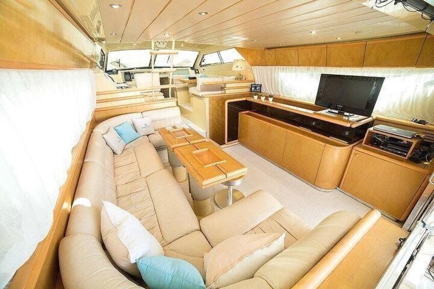 A yacht interior with a large L-shaped sofa, a dining table, and a TV. 4