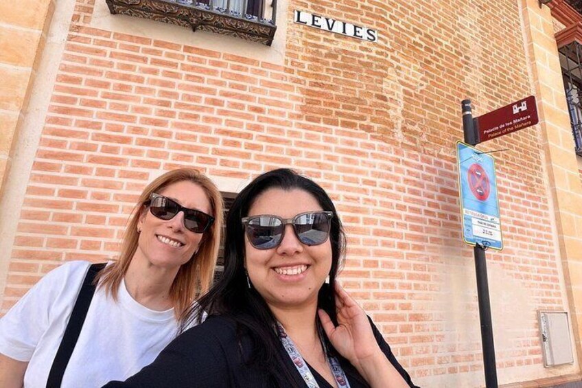 Two people standing in front of a brick building with a sign that reads 'LEVIES'. 5
