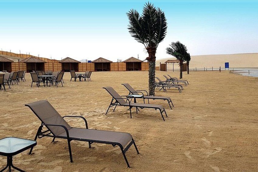 Ein Sandstrand mit Liegestühlen und Sonnenschirmen. 3