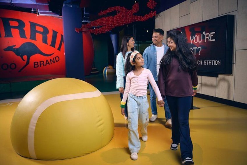 A large yellow ball, people walking, and a wall with 'ARRI' and 'YOU'RE HERE?' text. 2