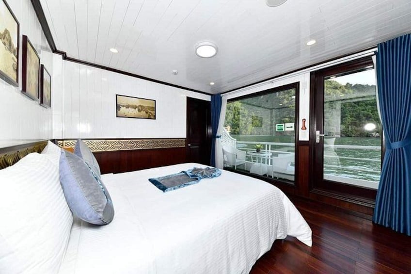 A bedroom with a large bed, a window with curtains, and a view of a river. 2