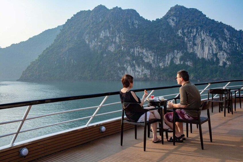 Two people dining on a boat with a mountainous landscape in the background. 2