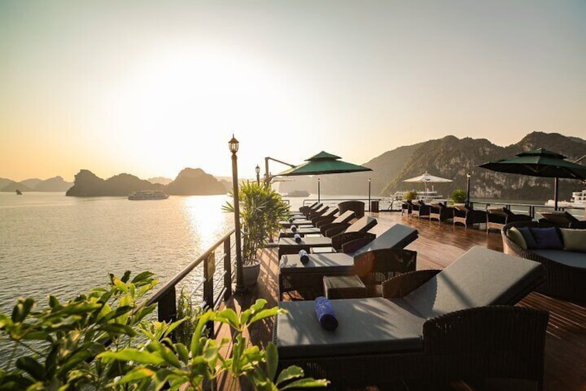 A waterfront terrace with lounge chairs and umbrellas, overlooking a calm sea and distant islands. 4