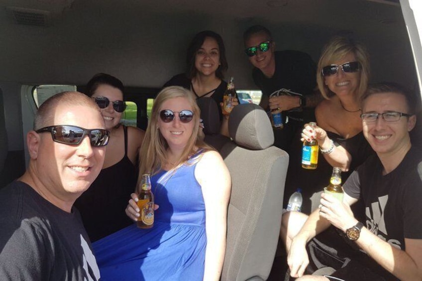 A group of people in a vehicle, some holding drinks. 2