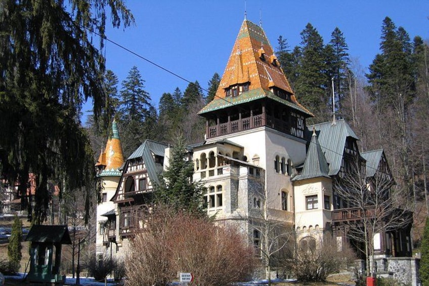 A large, ornate building with a prominent tower and a smaller turret, surrounded by trees and snow. 3