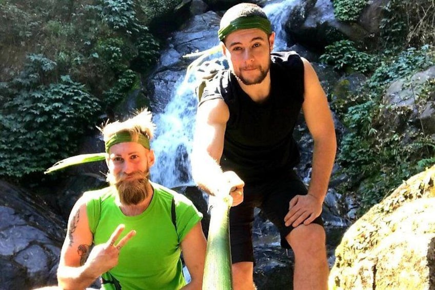Two people in a natural setting with a waterfall in the background. 5