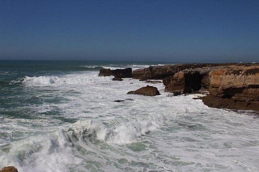 A rocky coastline with waves crashing against the rocks under a clear sky. 5