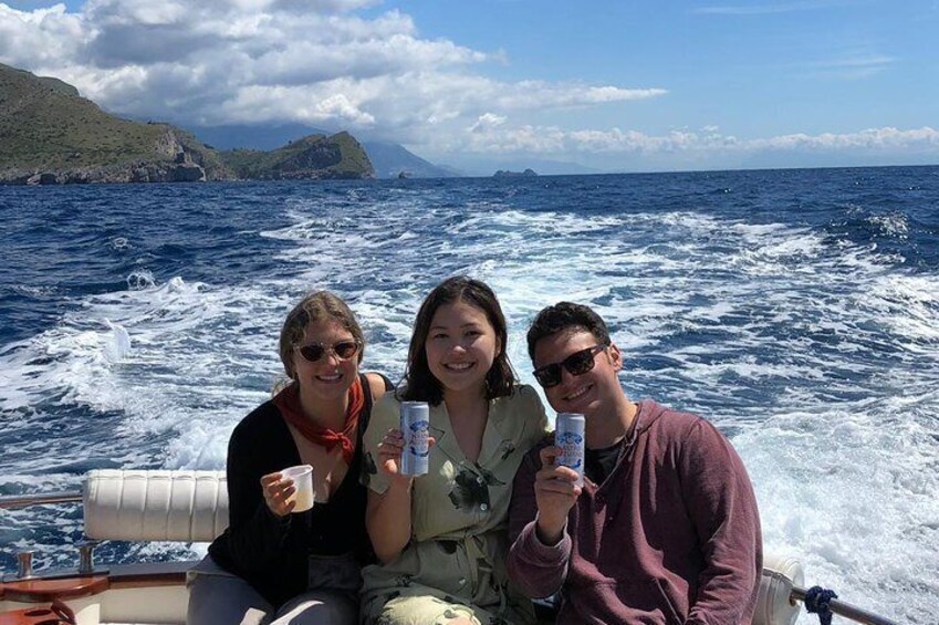 Three people on a boat in the ocean with waves around them. 4