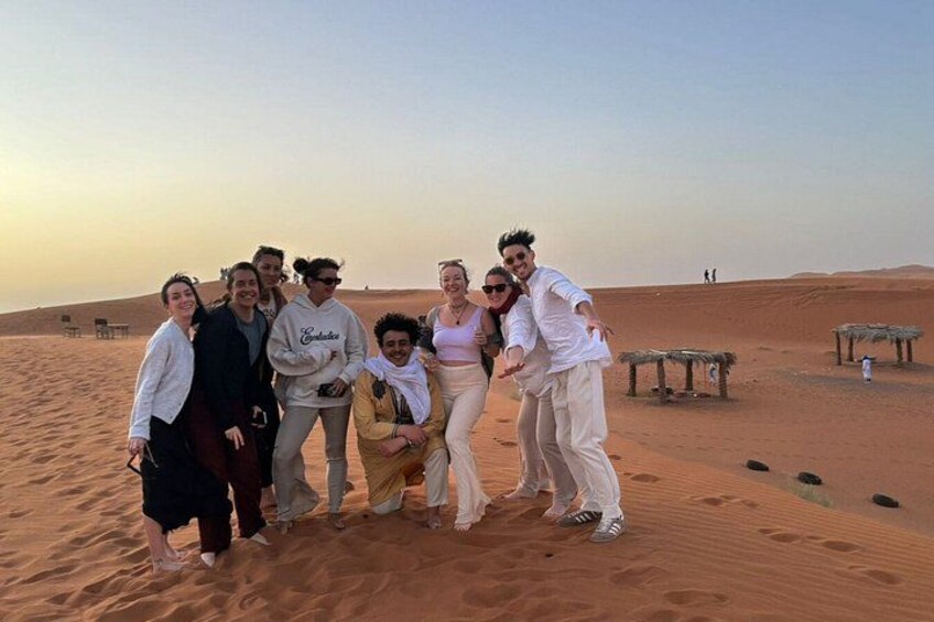 Un grupo de personas de pie en una playa arenosa con dunas al fondo. 2