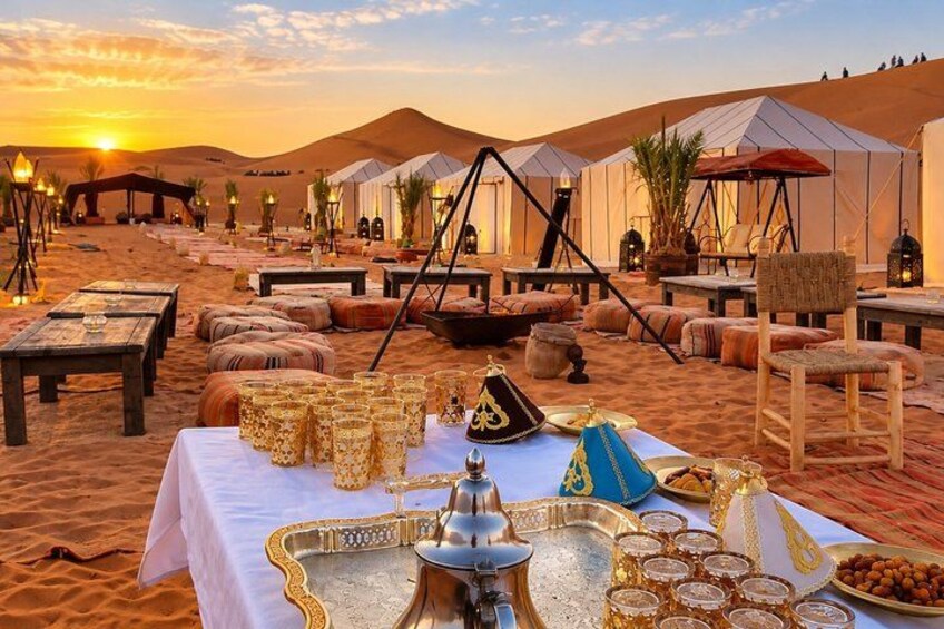 A desert camp with tents, tables set for a meal, and desert scenery. 1