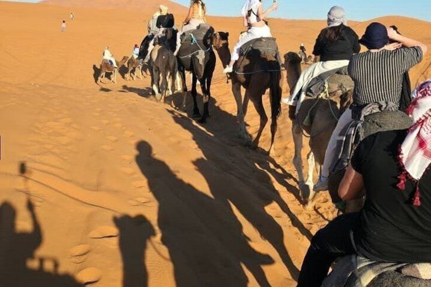 Un grupo de personas montando camellos a través de un paisaje desértico. 2