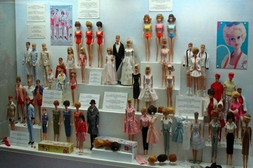 Una colección de muñecas exhibidas en estanterías con carteles informativos. 2