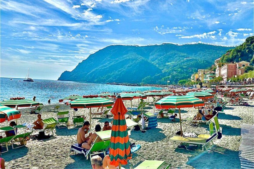 A beach with people sunbathing, umbrellas, and boats in the water. 4