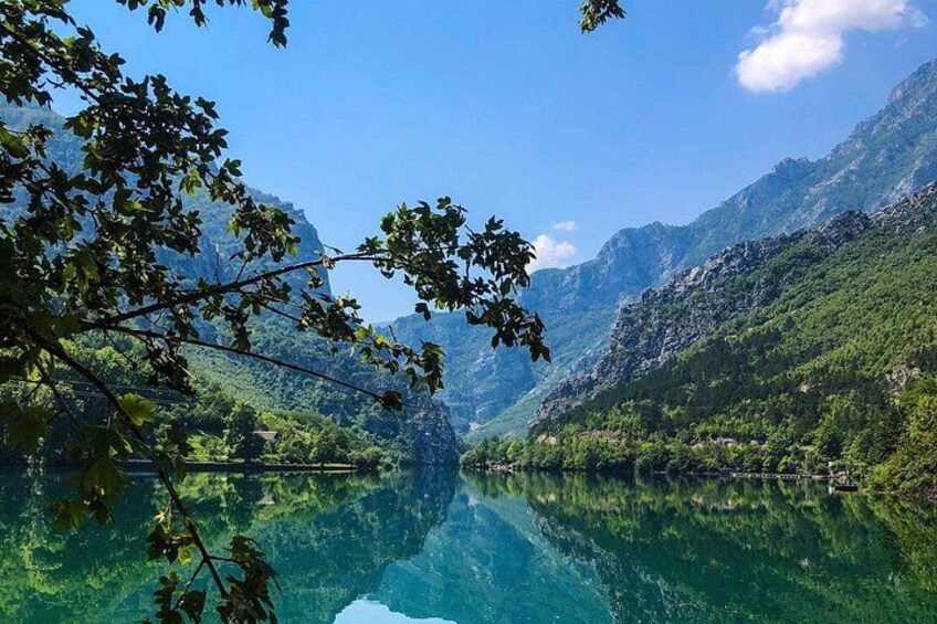 Ein klarer Bergsee, umgeben von üppigem Grün und felsigen Bergen. 2