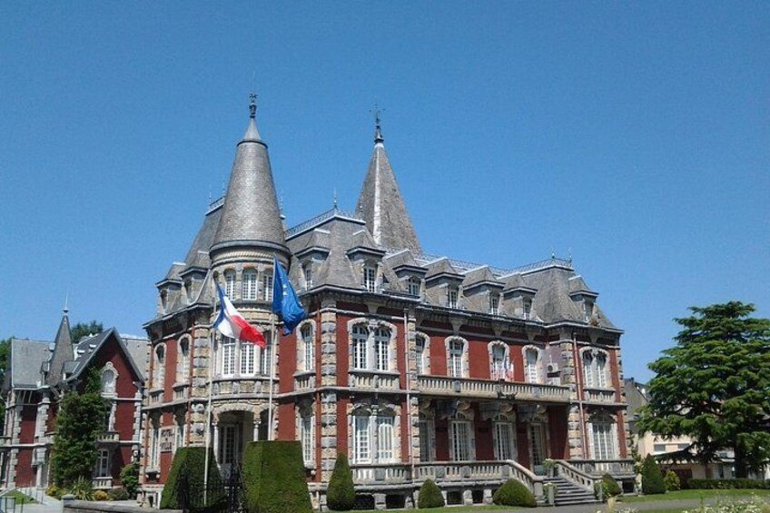 Een groot, versierd gebouw met meerdere torens en vlaggen, waaronder de Franse vlag. 3
