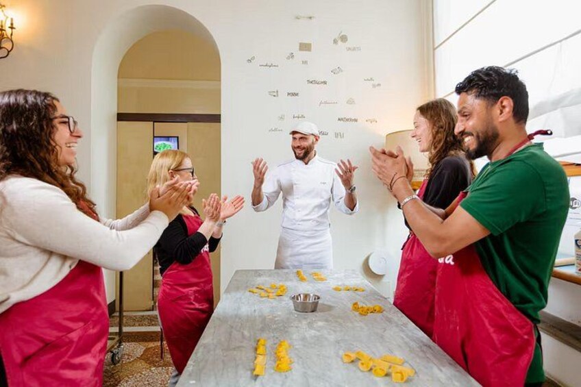 Un grupo de personas aplaudiendo alrededor de una mesa con comida. 2
