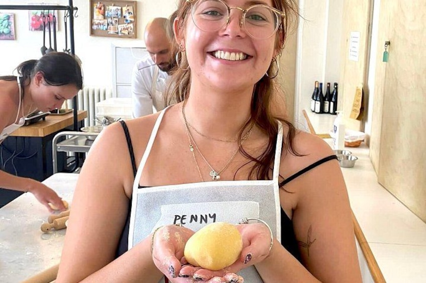 Une personne tenant une boule de pâte, portant un tablier sur lequel est inscrit le mot « PENN ». 2