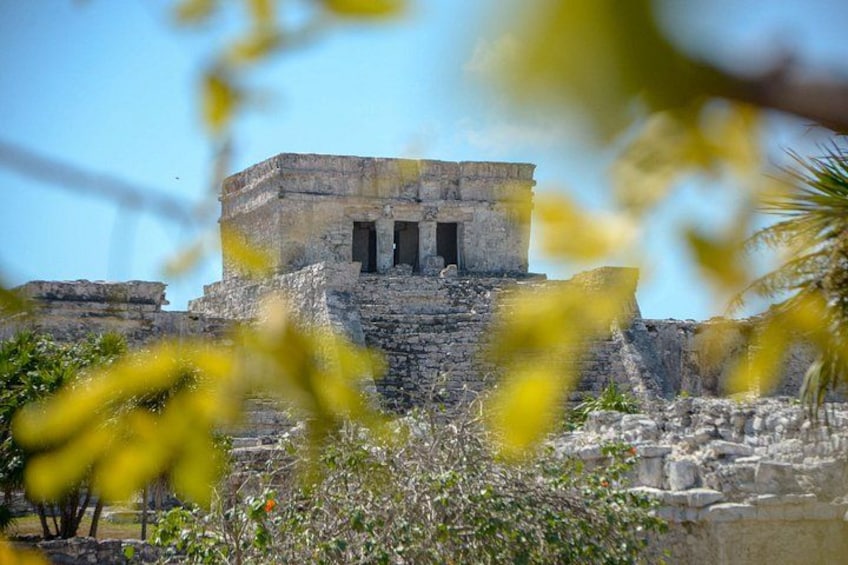 An ancient stone structure with three doorways, surrounded by vegetation and ruins. 2